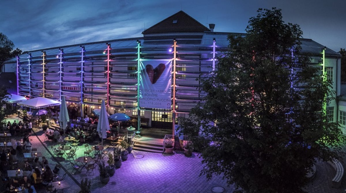 Terrasse der Cantina vor der abendlich beleuchteten Fassade der Pasinger Fabrik