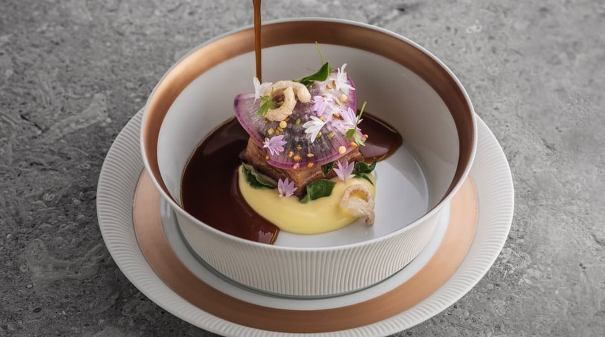 Gericht mit Blüten, das mit dunkler Sauce angegossen wird