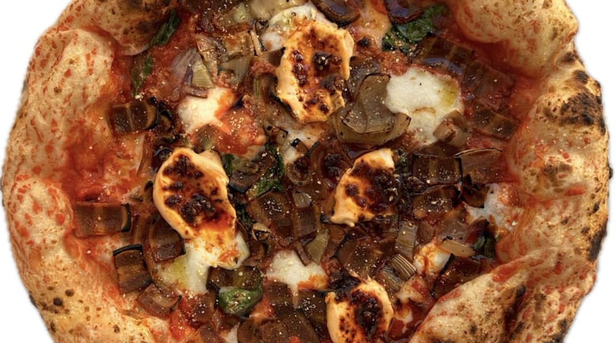Vegane Pizza mit dunklem Belag, Käsetupfen und Basilikum