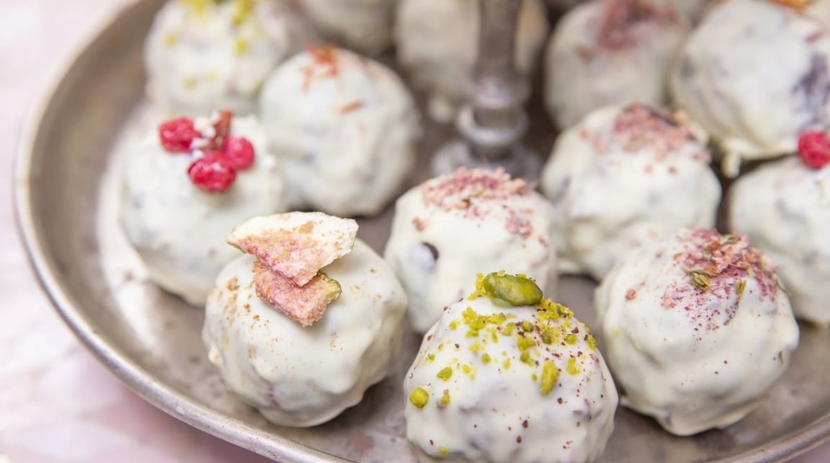Pralinen mit weißer Schokolade, Pistazien und Rosenblüten auf einer Metallplatte