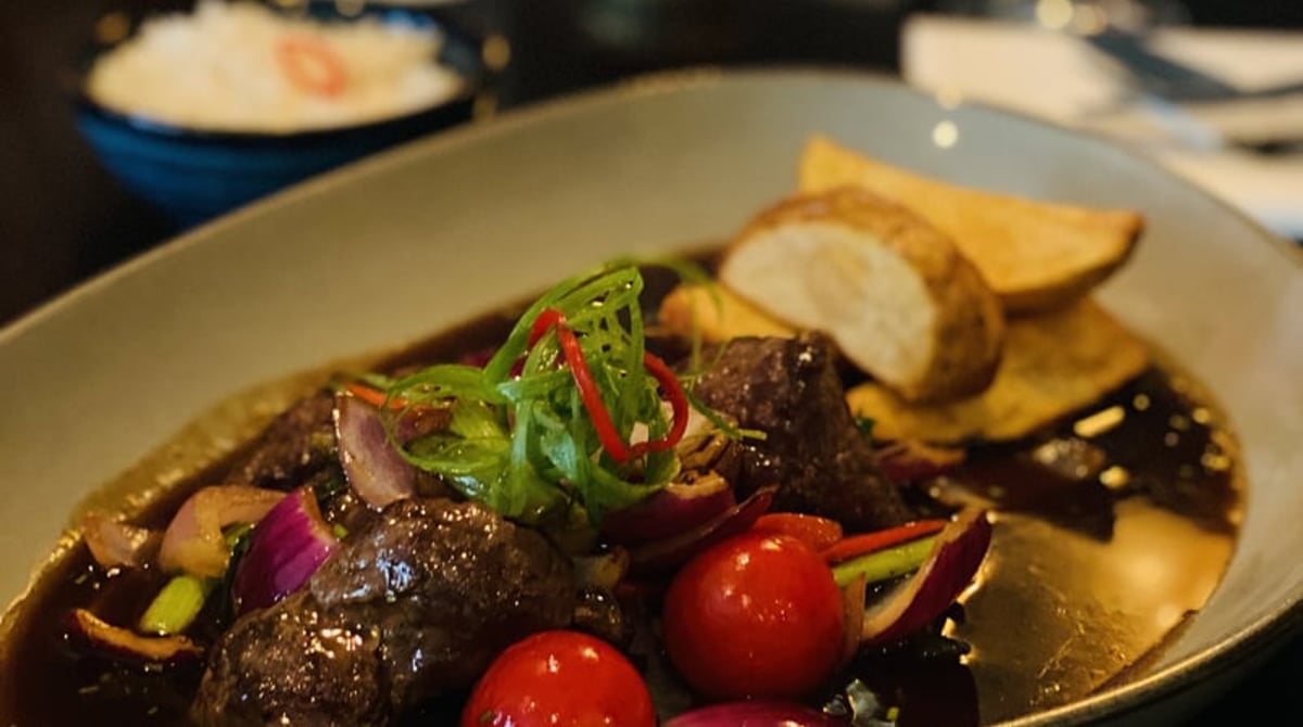 Peruanisches Rindfleischgericht mit Kirschtomaten, roten Zwiebeln und frittierten Kartoffeln im Nasca