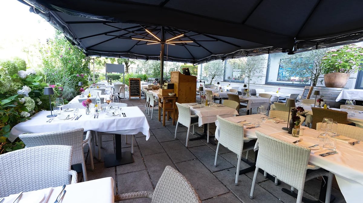 Überdachte Terrasse des PURO bar e cucina in München-Neuhausen mit eingedeckten Tischen