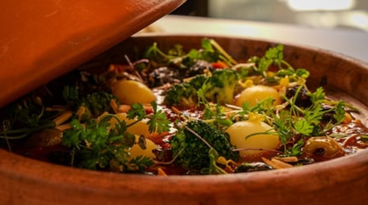 Tajine-Gericht in der Tonschale mit Kräutern und Gemüse