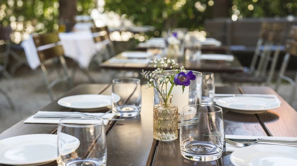Gedeckte Tische auf der begrünten Terrasse des Orta in München-Schwabing