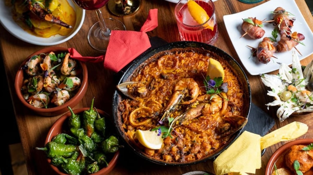 Gedeckter Tisch mit Paella, Tortilla, Pimientos de Padrón und weiteren Tapas
