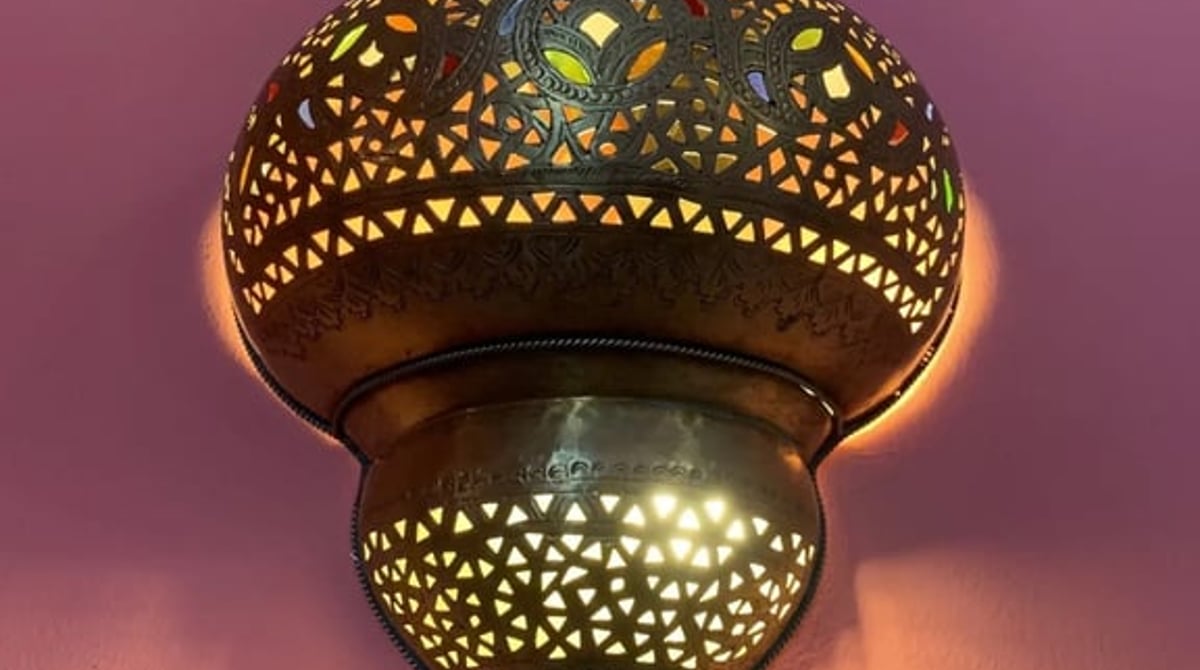 Durchbrochene Messinglampe vor violetter Wand im Ganga