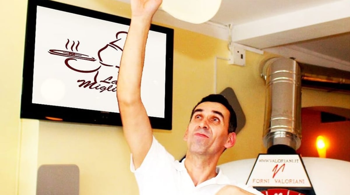 Pizzaiolo wirft den Teig vor dem Ofen der Pizzeria La Migliore