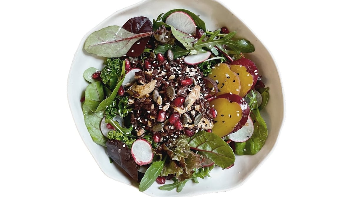 Bowl mit rotem Reis, Gemüse, Rote Bete, Granatapfelkernen und Kernen, von oben fotografiert