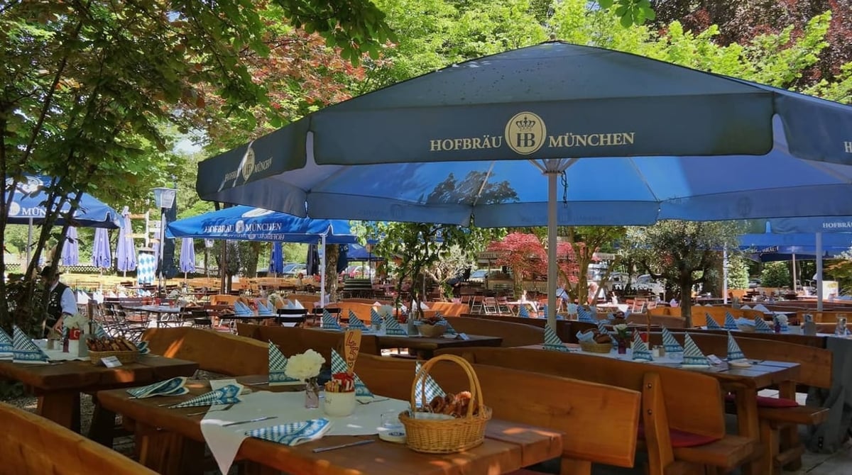Biergarten des Waldgasthofs Buchenhain mit gedeckten Tischen unter Sonnenschirmen