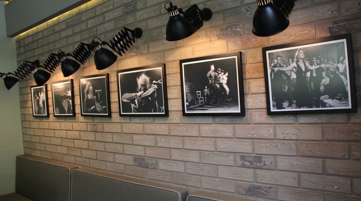 Backsteinwand mit gerahmten Schwarz-Weiß-Fotos und Spotlampen im Gastraum der Taverna Limani