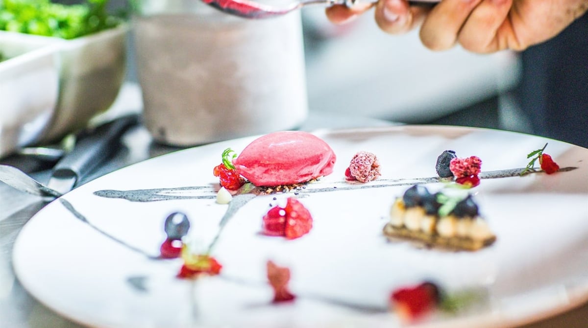 Dessert mit rotem Sorbet und Beeren auf einem weißen Teller