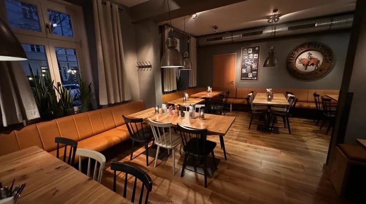 Restaurant von Ruff's Burger in der Occamstraße mit Fenstern, Sitzbank und eingedeckten Holztischen