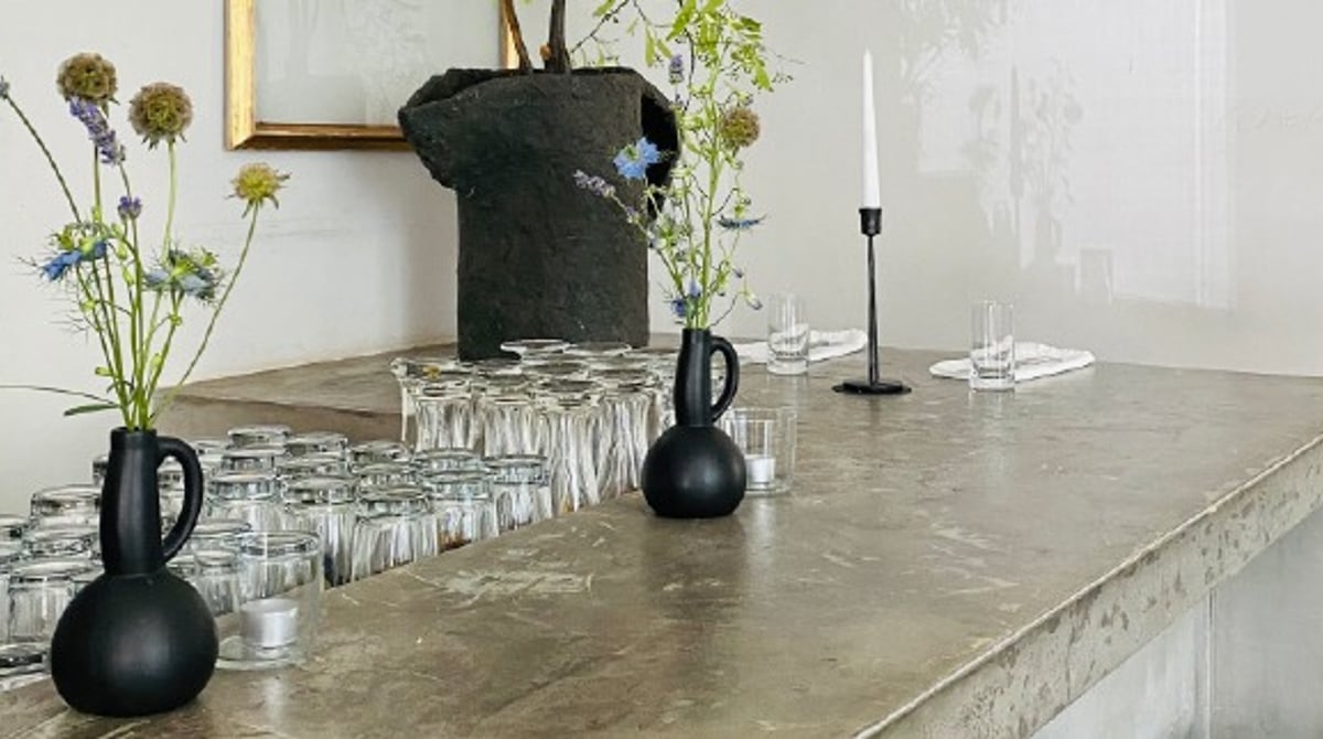 Bar des Le Refuge mit Gläsern, schwarzen Vasen mit Wiesenblumen und Kerzenleuchtern