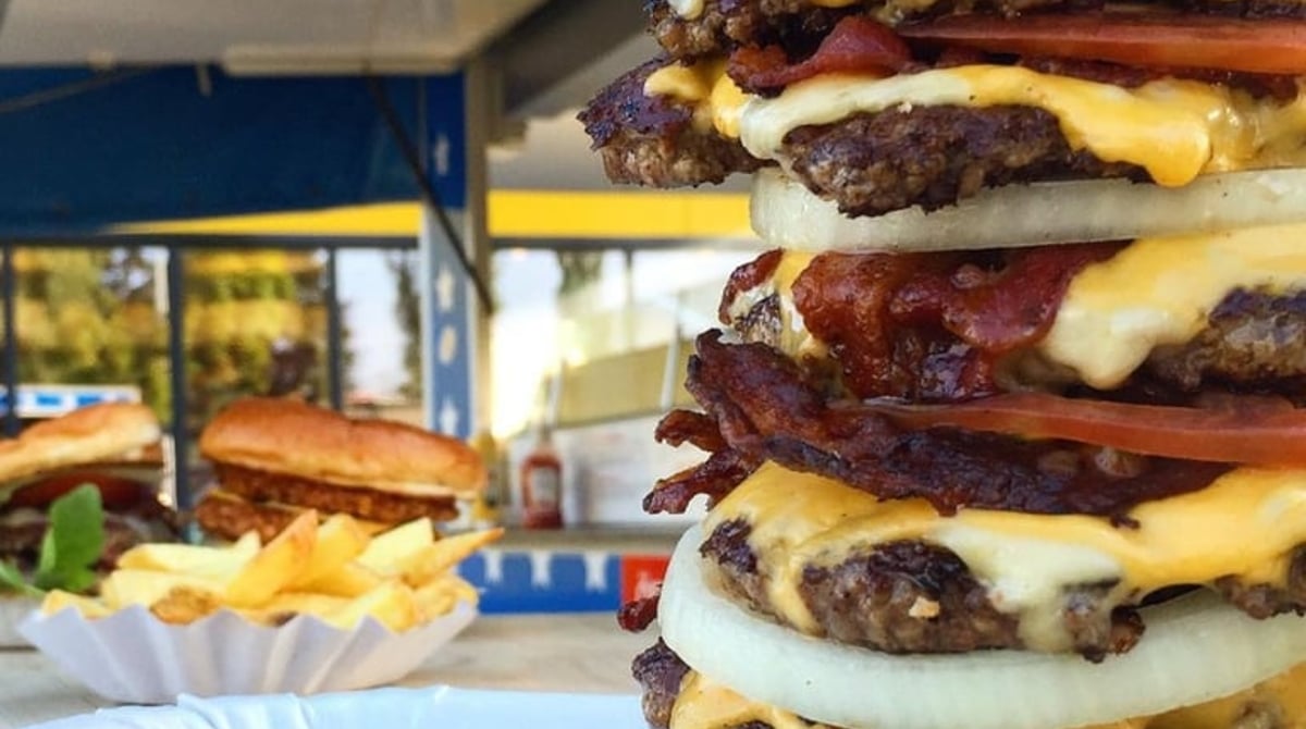 Turm aus mehreren Burger-Patties mit Käse und Bacon vor dem Foodtruck der American Burger Bar