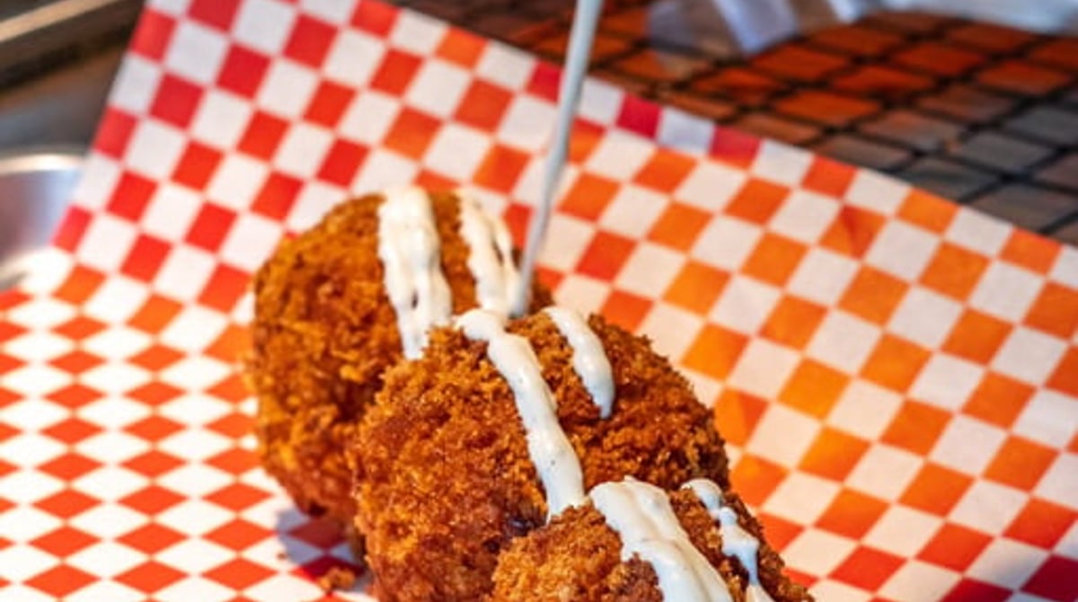 Frittierte Mac'n'Cheese-Balls mit Ranch-Sauce auf rot-weiß kariertem Papier