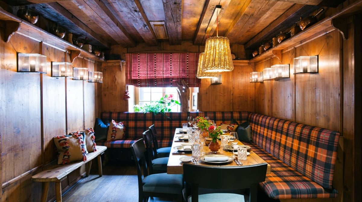 Ofenstube mit Holzvertäfelung, Eckbank mit Karostoff und langer Tafel