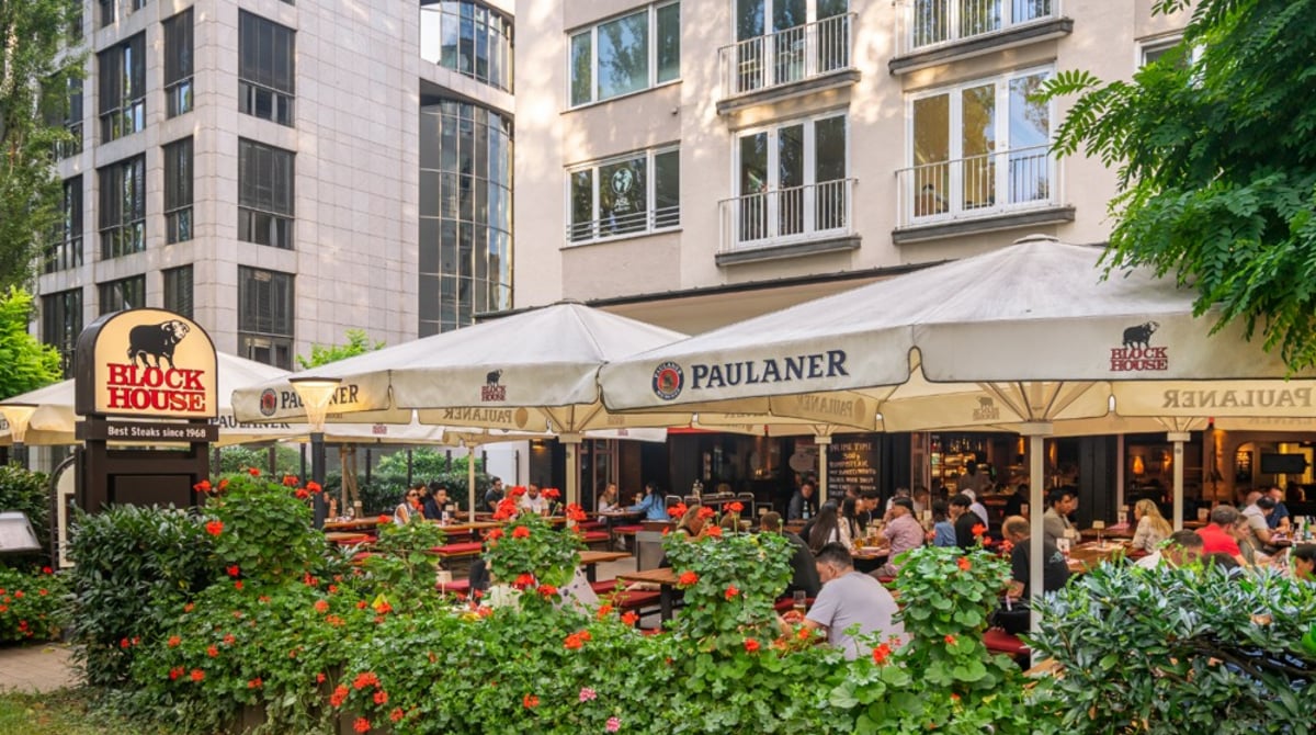Sonnengeschützte Terrasse des Block House an der Leopoldstraße mit Gästen und Sonnenschirmen