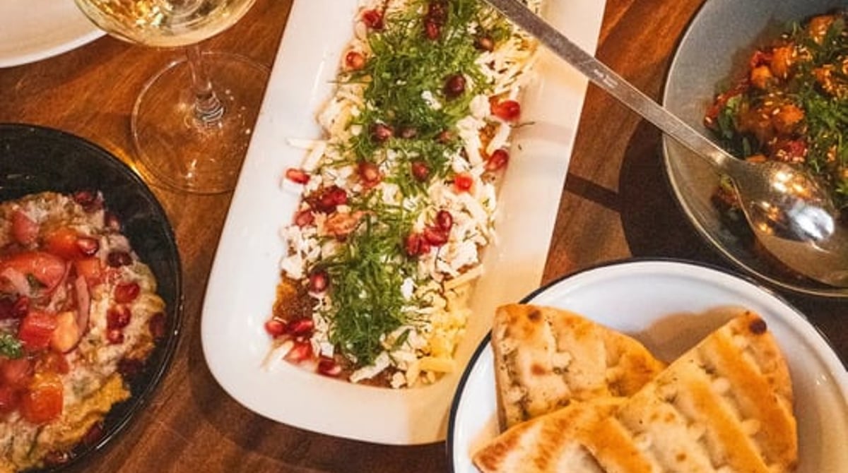 Tisch mit mehreren Mezze-Tellern, Fladenbrot und Weißwein im Orta