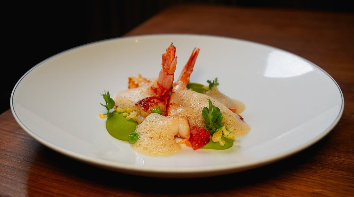 Garnelen mit grünen Kräutern und Sauce auf einem weißen Teller