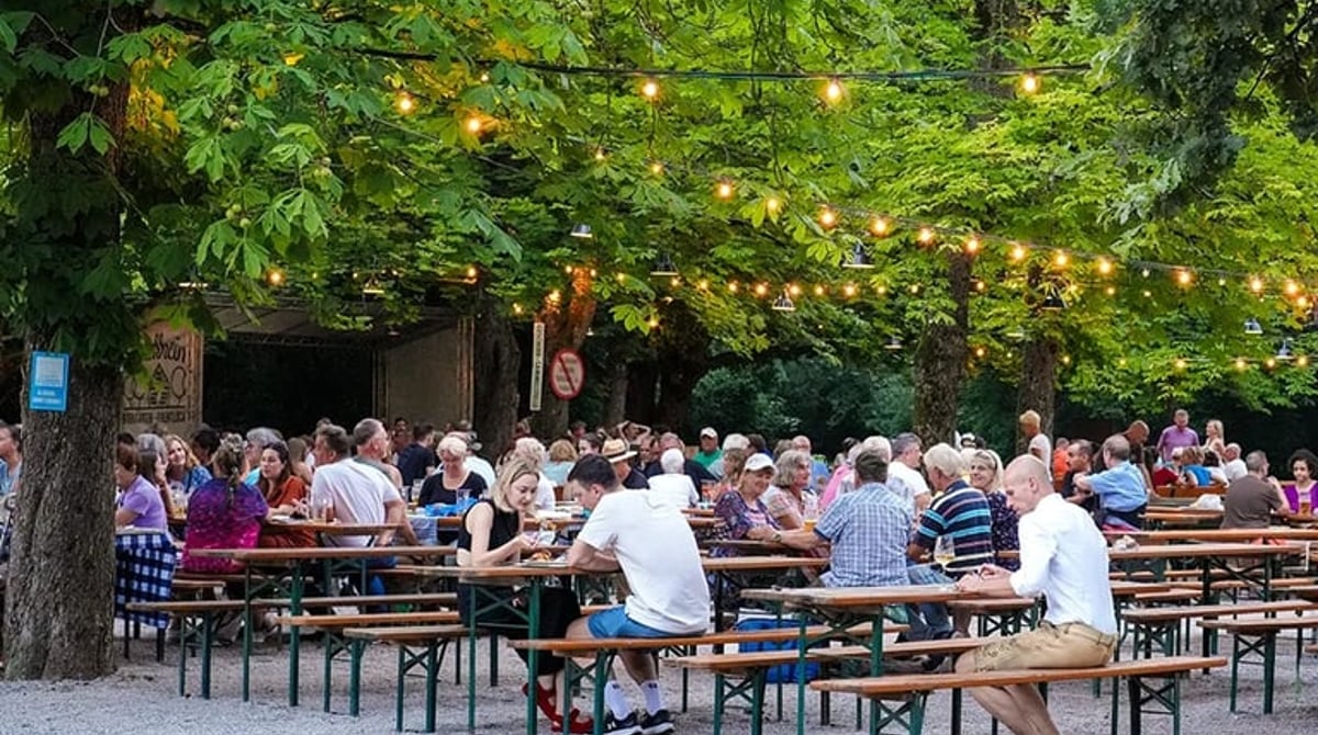 Abendstimmung mit Lichterketten und vollen Bierbänken unter den Kastanien