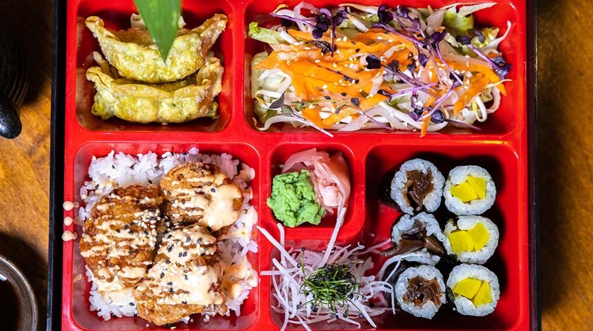 Rote Bento-Box mit Gyoza, Salat, Reis mit frittiertem Hähnchen und Maki