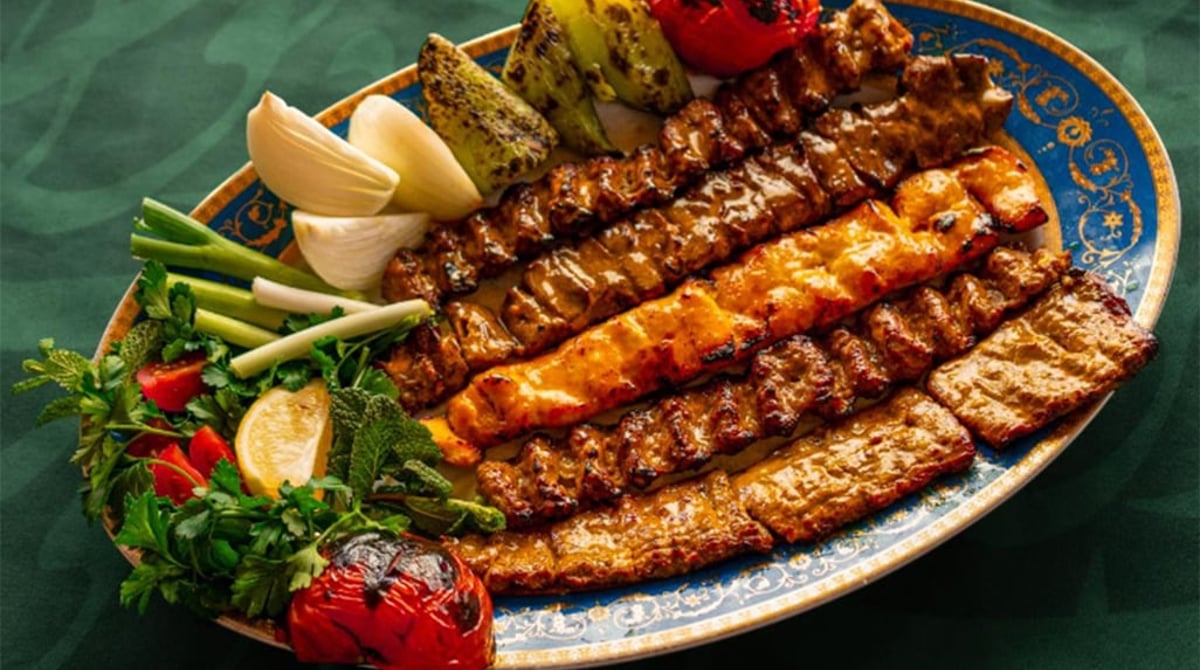 Gemischte Kebab-Platte mit gegrilltem Gemüse, Tomaten und Limette auf einem Servierteller im Diwan