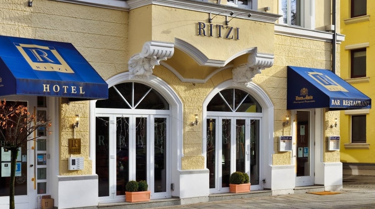 Eingang von Hotel, Bar und Restaurant Ritzi mit blauen Markisen und Rundbogenfenstern