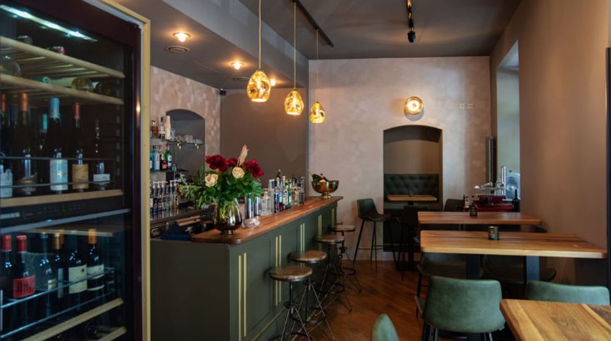 Gastraum des Mio Tapas mit Bar, Weinregal und Holztischen