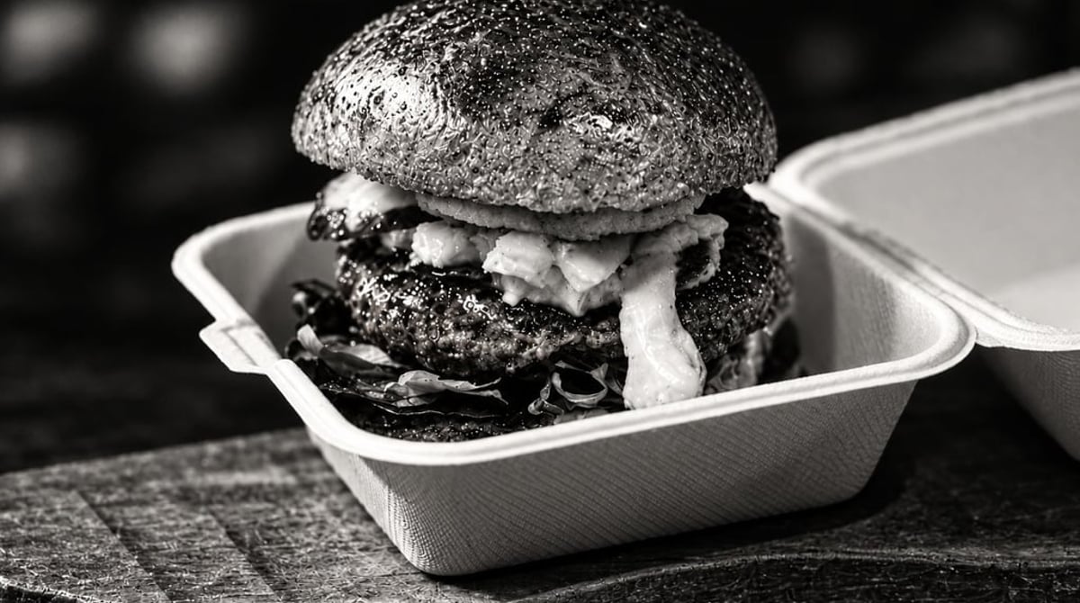 Doppelter Burger mit Bacon und Käse in einer Take-away-Box, Schwarz-Weiß-Aufnahme