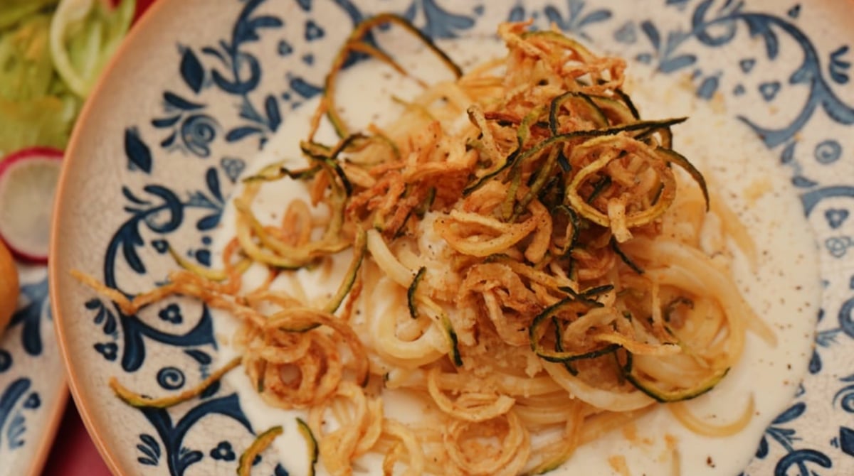 Pici mit Pecorino und knusprigen Zucchini-Chips auf blau-weißem Keramikteller