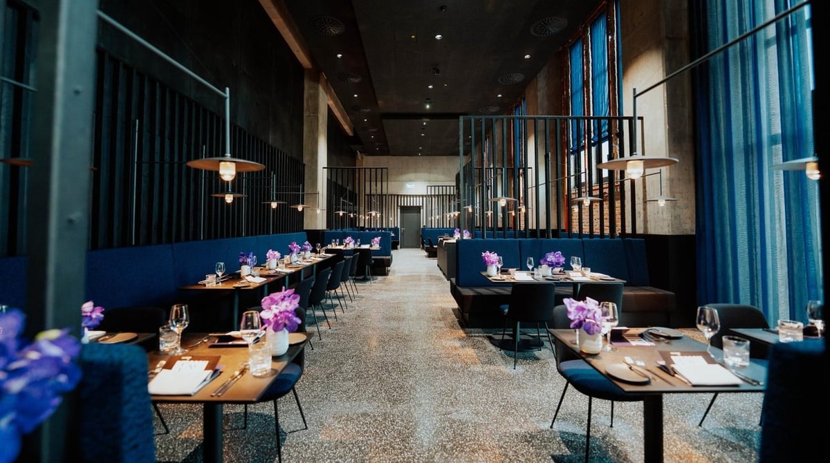 Gastraum des Restaurants Zeitlang im Bergson Kunstkraftwerk mit blauen Bänken und gedeckten Tischen