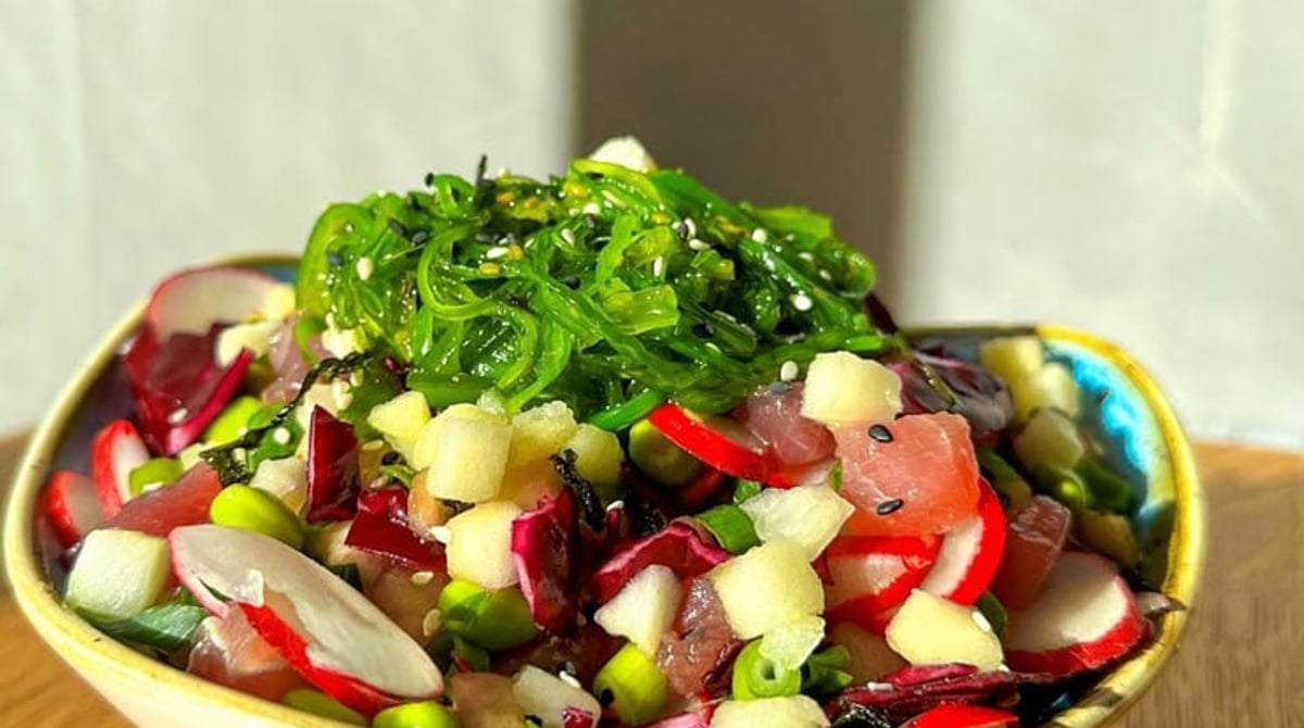 Poke Bowl mit Thunfisch, Radieschen, Edamame und Seetangsalat in einer Keramikschale