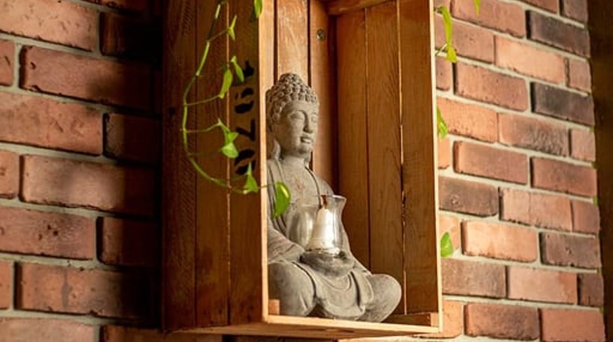 Buddha-Figur in einer Holzkiste vor Backsteinwand im RYU