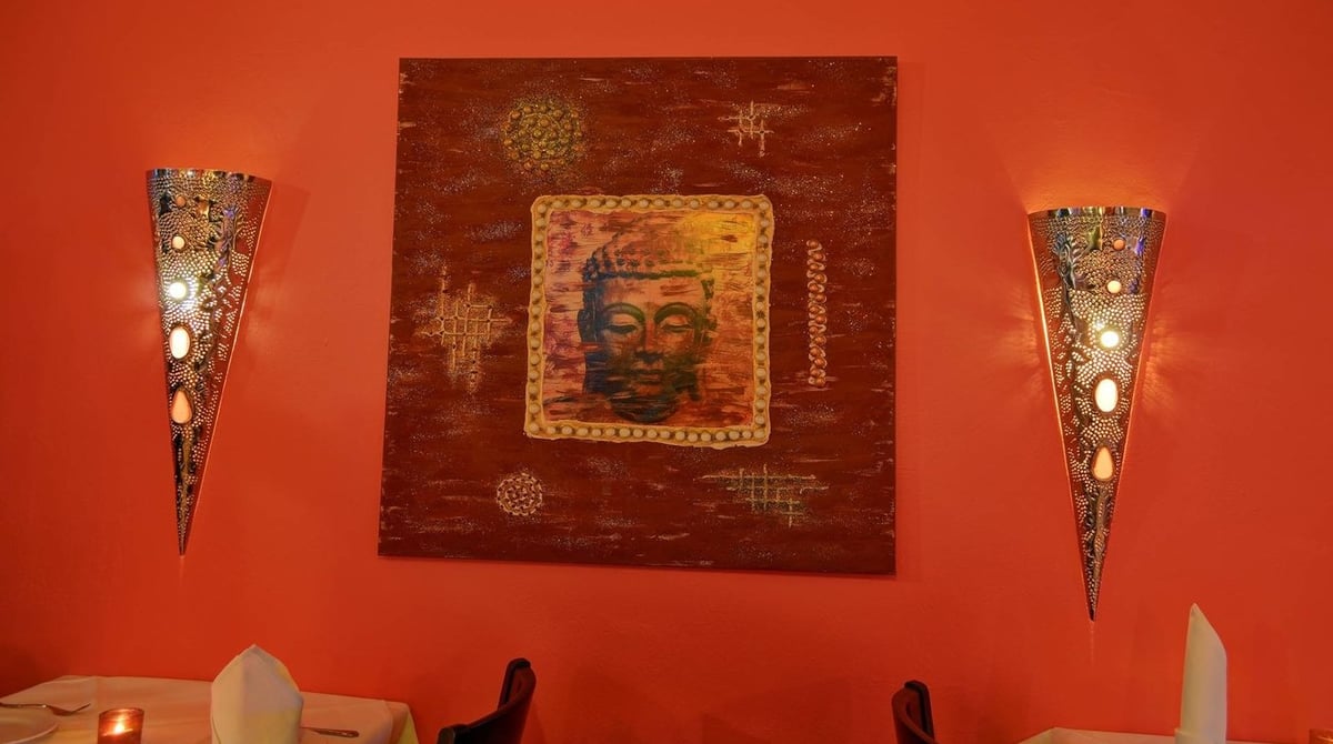 Rote Wand mit Schnitzbild und zwei Wandleuchten im Palast der Winde