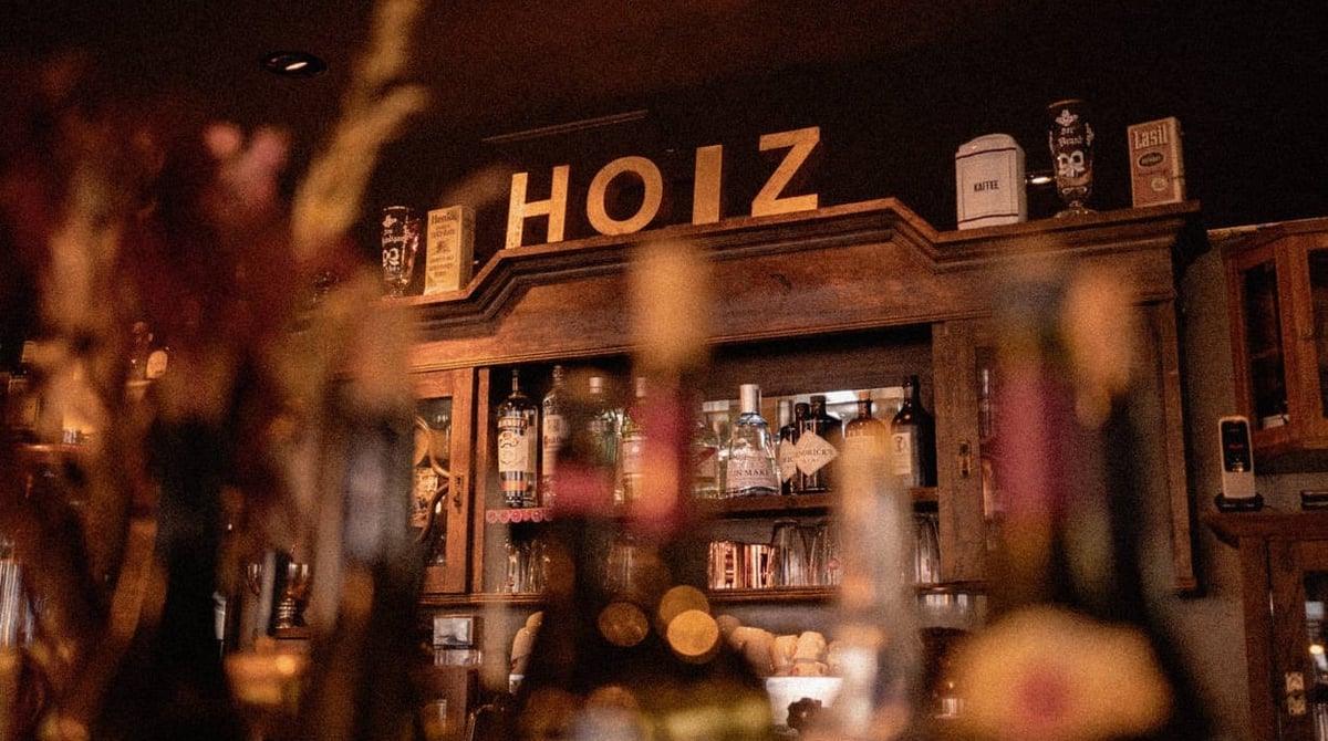 Holzregal mit dem Hoiz-Schriftzug und Flaschen hinter der Bar