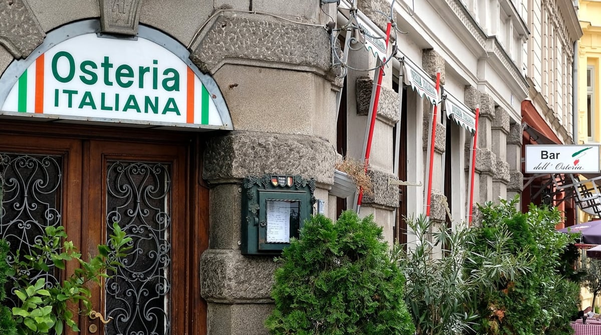 Eingang der Osteria Italiana in der Schellingstraße mit Steinfassade, Holztür und Schild