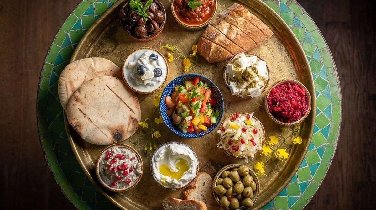 Meze-Platte mit Pita, Salaten und Dips auf einem Tablett im Nana
