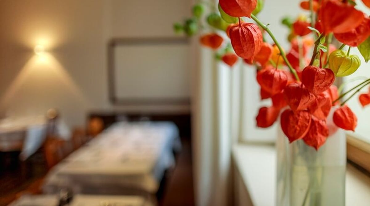 Gastraum des BROEDING mit gedeckten Tischen, im Vordergrund eine Vase mit Lampionblumen