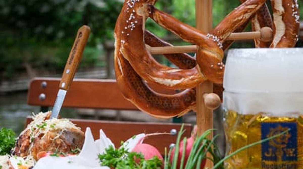 Brotzeitplatte mit Brezn, Käse und Radieserl neben einer Maß Augustiner