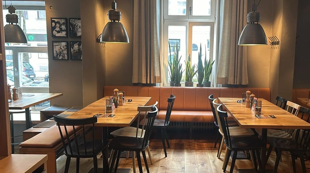 Gastraum von Ruff's Burger in der Occamstraße mit Holztischen, Lederbank und Industrieleuchten