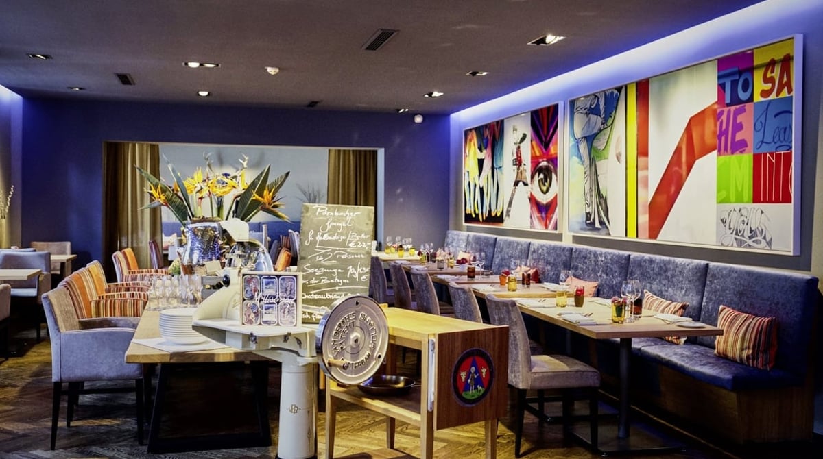 Gastraum des Blauen Bocks mit Aufschnittmaschine, gedeckten Tischen und Pop-Art-Bildern
