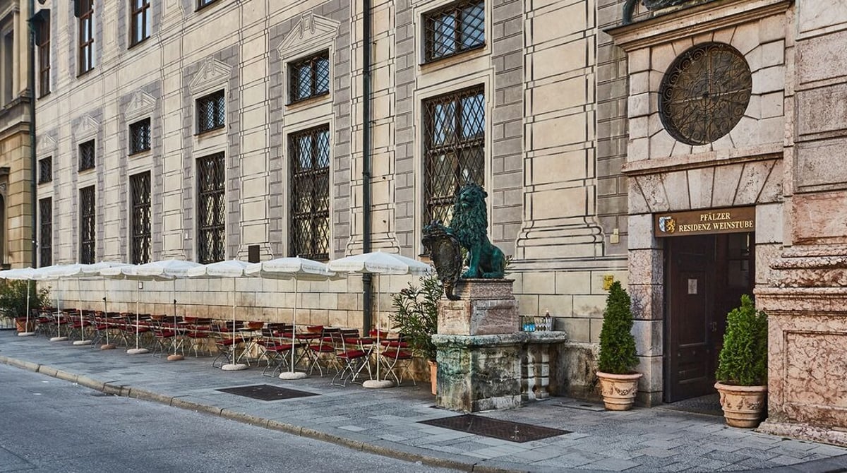 Eingang der Pfälzer Residenz Weinstube an der Residenzstraße mit Sonnenschirmen und Tischen davor