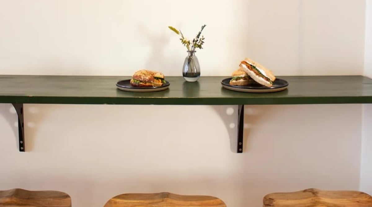 Wandregal mit zwei Tellern, Vase und Holzhockern im Barista Sistar