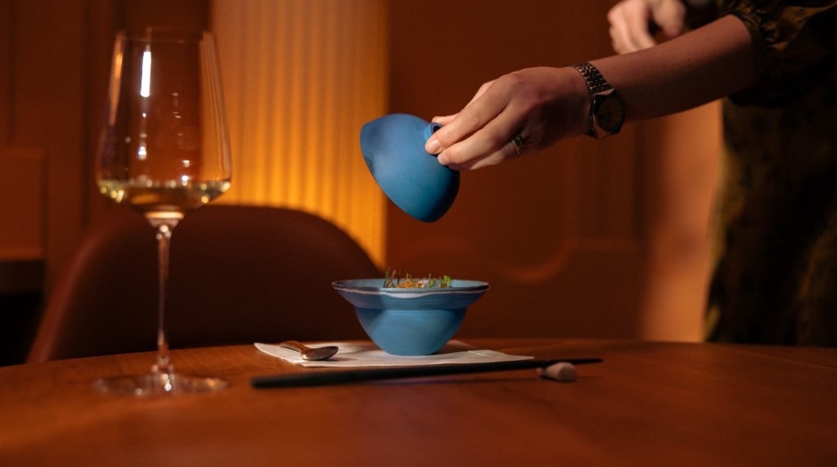 Eine blaue Schale wird auf dem Tisch neben einem Weinglas serviert