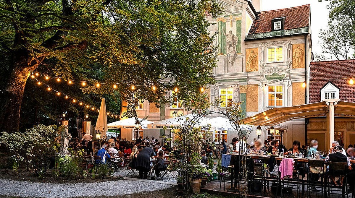 Gäste am Abend im Schlössl-Garten unter Lichterketten vor dem Asam Schlössl