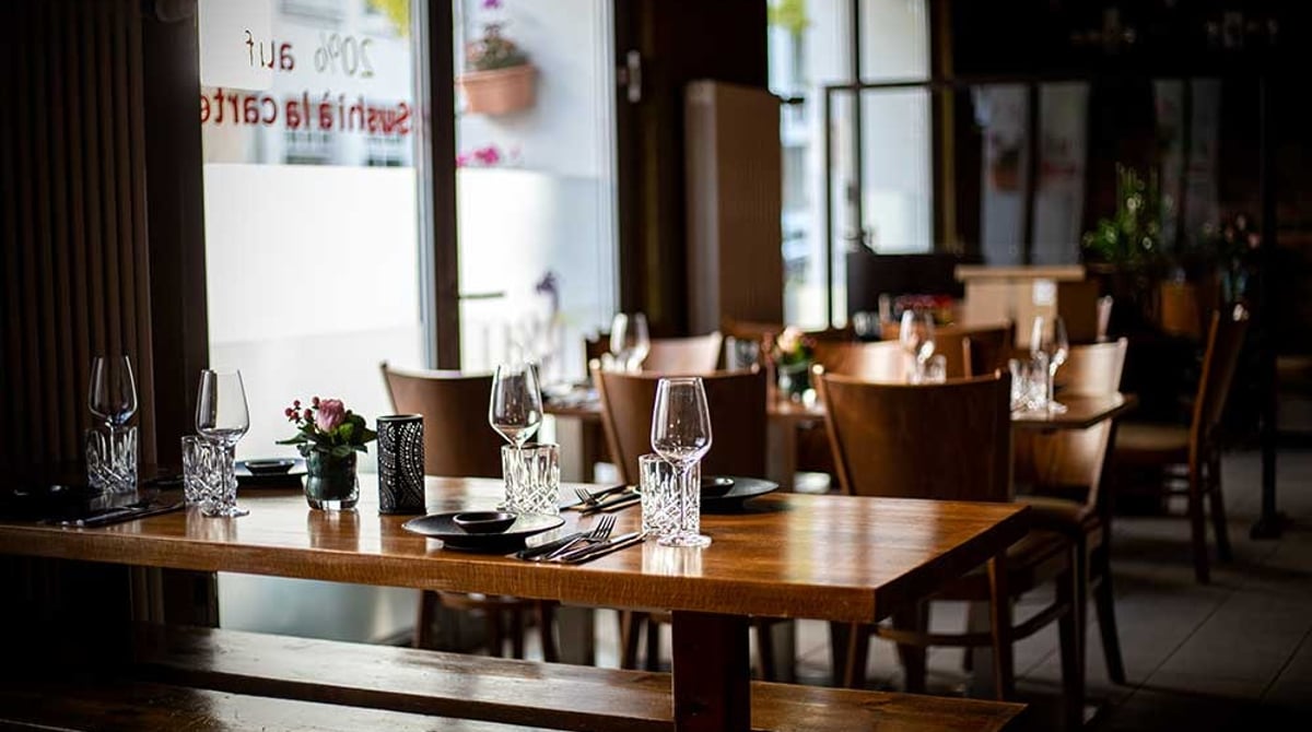 Gedeckte Holztische mit Gläsern und Blumen im Gastraum des RYU an der Blutenburgstraße