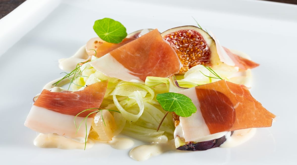 Vorspeise mit Schinken, Feige und Fenchel auf einem weißen Teller
