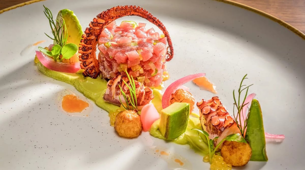 Tatar mit Pulpo, Avocado und eingelegten Zwiebeln auf einem hellen Teller
