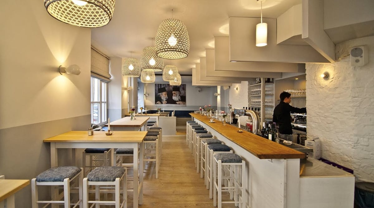 Bar mit langer Holztheke, Barhockern und Pendelleuchten in der Taverna Melina