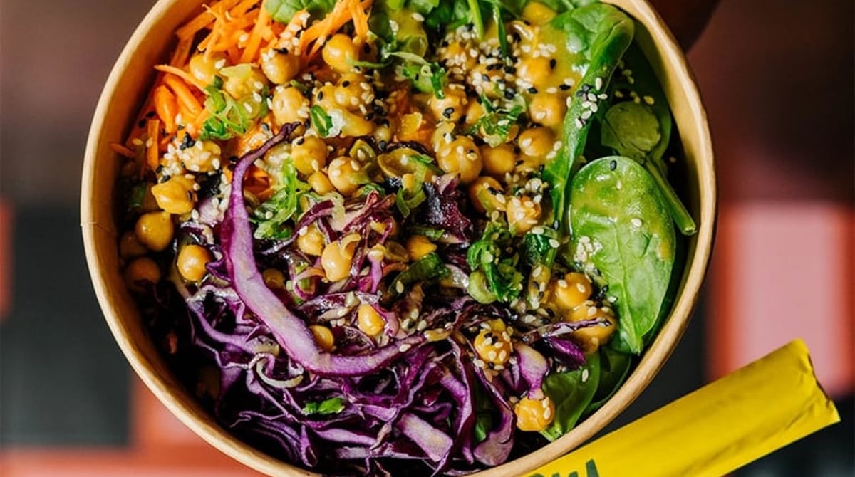 Bowl mit Kichererbsen, Rotkohl und Karotten in der Hand gehalten